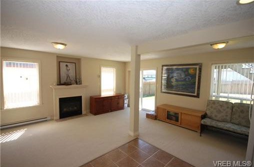 Ground floor living room with door that opens to back yard, note fireplace, Mamich circle, Victoria, BC 2014 real estate listing